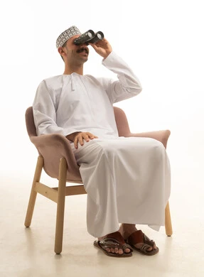 Saudi Man in Traditional Thobe Using Binoculars