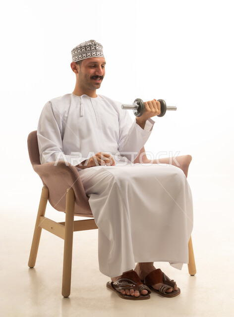 رجل سعودي بالثوب التقليدي يمارس رياضة رفع الأثقال