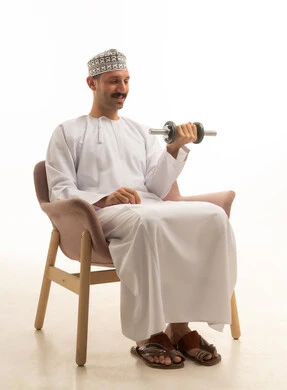 رجل سعودي بالثوب التقليدي يمارس رياضة رفع الأثقال