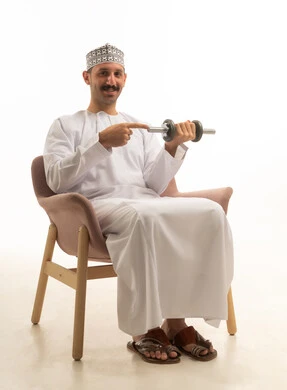 رجل سعودي بالزي التقليدي يمسك ثقلاً رياضياً