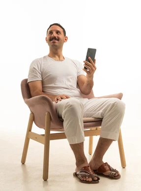 رجل سعودي يجلس على كرسي ممسكاً بهاتف ذكي