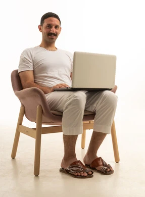 رجل سعودي يستخدم كمبيوتر محمول على خلفية استوديو بيضاء