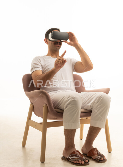 رجل سعودي يستخدم نظارة الواقع الافتراضي جالسًا