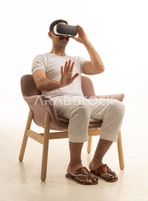 Saudi Man Using VR Headset Sitting in Modern Armchair