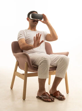Saudi Man Using VR Headset Sitting in Modern Armchair