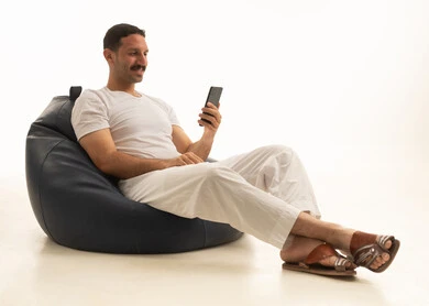 Saudi Man Sitting on Bean Bag Using Smartphone in Studio