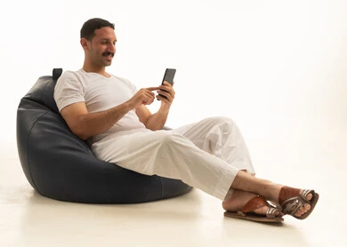 رجل سعودي يستخدم هاتف ذكي على مقعد محشو