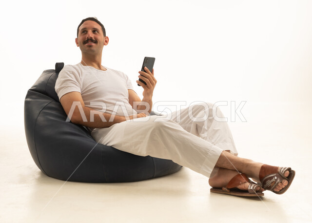 رجل سعودي يجلس على بين باج مع هاتف ذكي