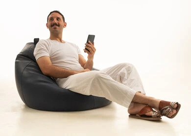 رجل سعودي يجلس على بين باج مع هاتف ذكي