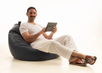 رجل سعودي يجلس على كرسي بين باج مع جهاز لوحي