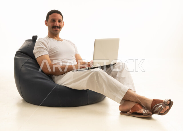 رجل سعودي يستخدم اللابتوب على كرسي بين باج