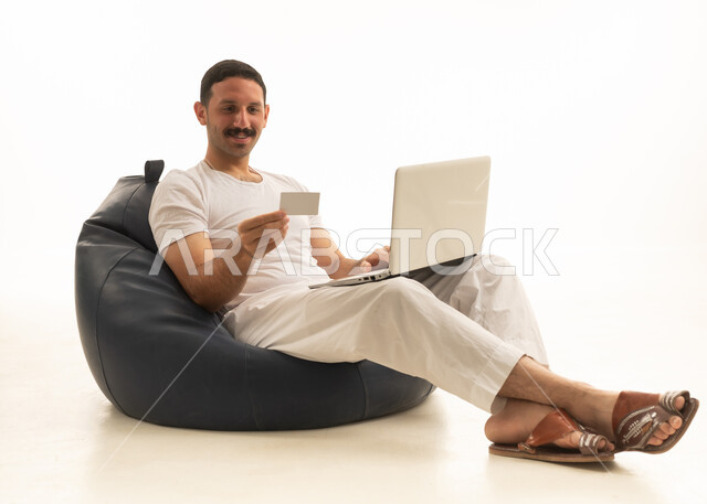 Saudi Man Online Shopping with Credit Card and Laptop
