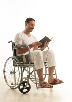 رجل سعودي على كرسي متحرك يقرأ كتاباً