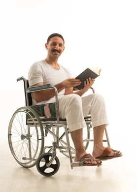 رجل سعودي على كرسي متحرك يقرأ كتاباً خلفية بيضاء