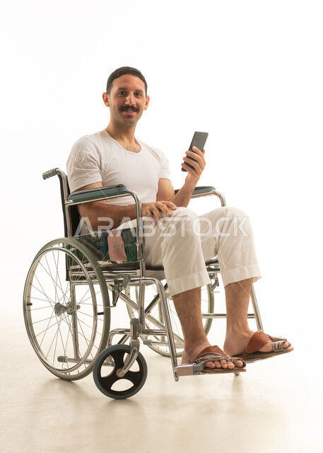 Saudi Man in Wheelchair Using Smartphone Studio Shot