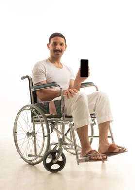 رجل سعودي على كرسي متحرك يحمل هاتف ذكي بشاشة فارغة