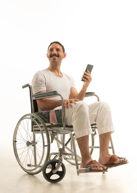 رجل سعودي على كرسي متحرك يحمل هاتف ذكي خلفية بيضاء