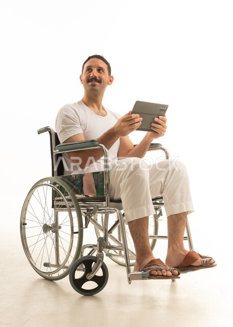 رجل سعودي على كرسي متحرك يستخدم جهاز لوحي