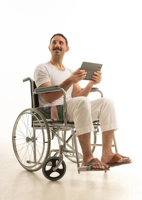 Saudi Man in Wheelchair Using Tablet on White Background