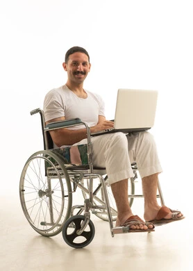 Saudi Man in Wheelchair Using Laptop on White Background