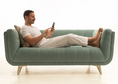 رجل سعودي يستخدم الهاتف الذكي على أريكة خضراء