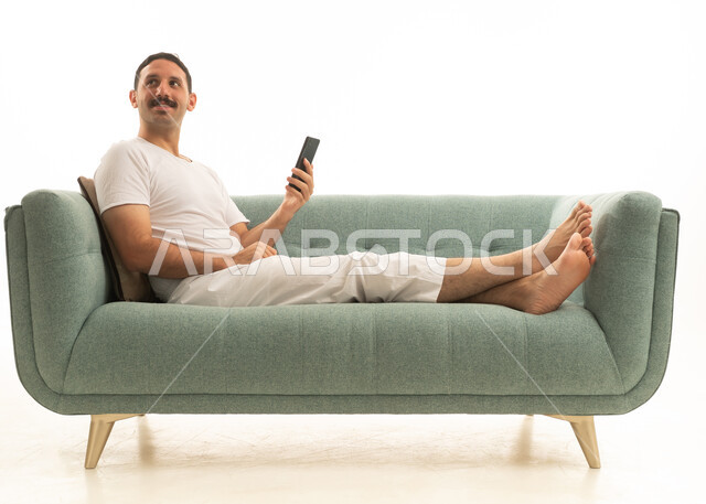 رجل سعودي على أريكة يستخدم الهاتف الذكي