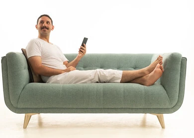 رجل سعودي على أريكة يستخدم الهاتف الذكي