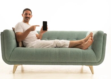 رجل سعودي يشير إلى شاشة هاتف ذكي على الأريكة