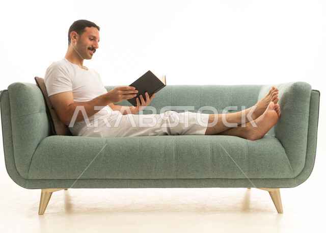 رجل سعودي يقرأ كتاباً على أريكة حديثة