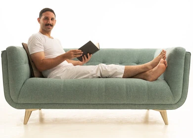 رجل سعودي يقرأ كتاباً على أريكة خضراء