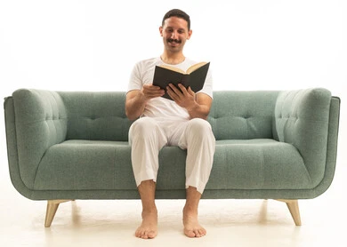 رجل سعودي يقرأ كتاباً على أريكة خضراء في الاستوديو