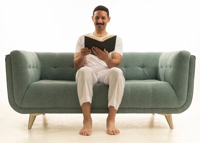 Saudi Man Reading a Book on Teal Sofa