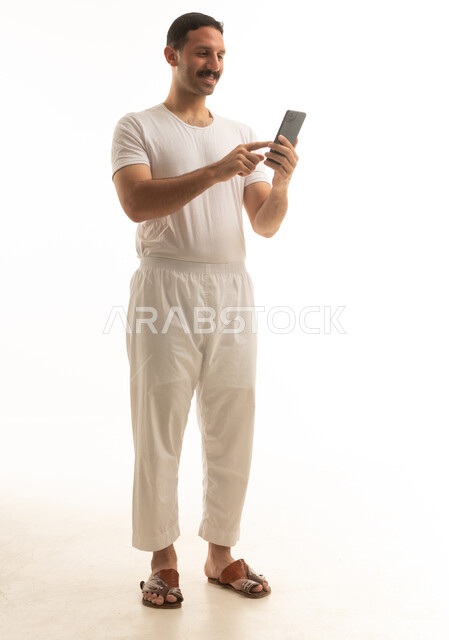 رجل سعودي يستخدم الهاتف الذكي على خلفية بيضاء