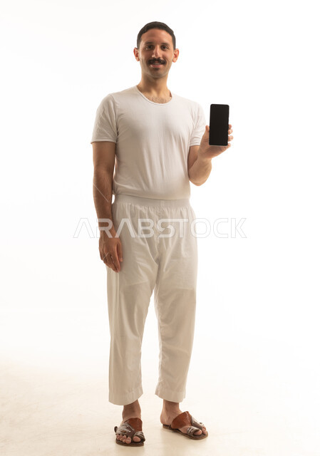 رجل سعودي يمسك هاتف ذكي بخلفية بيضاء