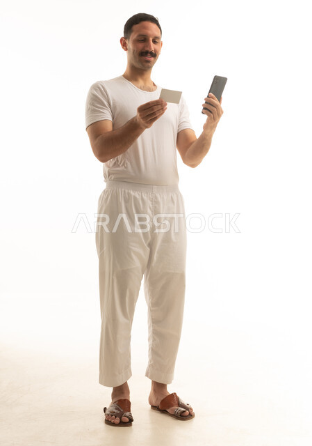 رجل سعودي يستخدم الهاتف والبطاقة البنكية في استوديو