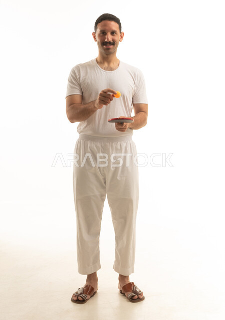 رجل سعودي يحمل مضرب تنس طاولة بخلفية بيضاء