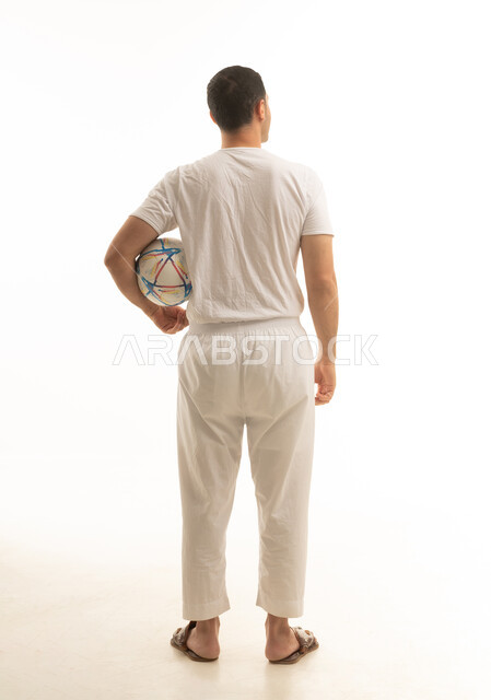 رجل عربي سعودي خليجي يرتدي الفانيلا والسروال يحمل بيده كرة قدم, تشجيع الفريق السعودي, كامل الجسم, خلفيه بيضاء
