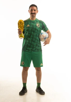 لاعب كرة قدم سعودي يحمل كأساً ذهبية وكرة قدم