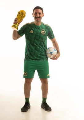 مشجع كرة قدم سعودي يحمل كأس العالم والكرة