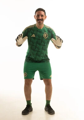 حارس مرمى سعودي بالزي الأخضر أمام خلفية بيضاء