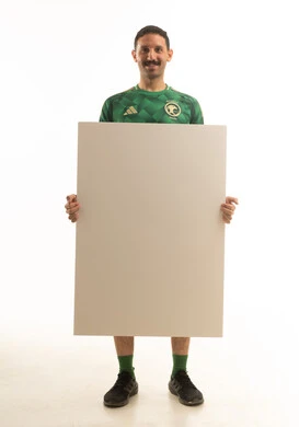 رجل عربي سعودي خليجي يرتدي الزي الرياضي يحمل لوحه اعلانيه بيضاء فارغه, الجسم بالطول الكامل, خلفيه بيضاء