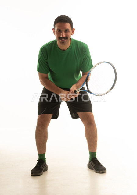 A Saudi Arabian Gulf Arab man wearing sports attire holding a tennis racket, engaging in enjoyable physical activity, full body, white background.