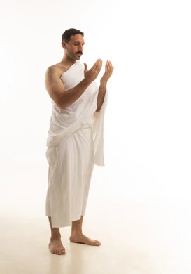 رجل سعودي يرتدي ملابس الإحرام ويدعو بخلفية بيضاء