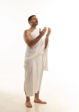 رجل سعودي يرتدي ملابس الإحرام ويدعو بخلفية بيضاء