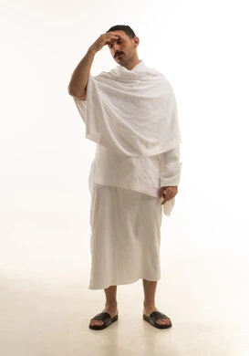 A portrait of an Arab Saudi Gulf man wearing white Ihram clothing, performing the rituals of Hajj and Umrah, worship and drawing closer to God, with a white background, full-body.