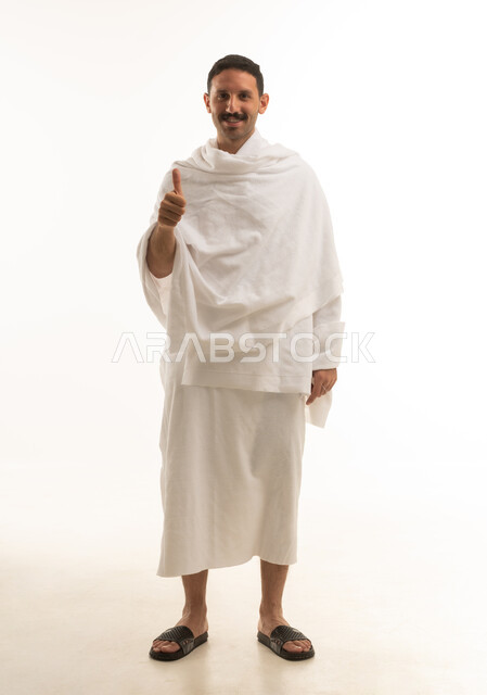 رجل سعودي بملابس الإحرام يرفع إبهامه علامة الرضا