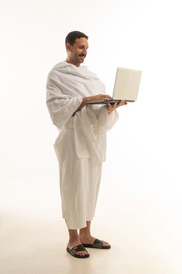 رجل سعودي بملابس الإحرام يحمل لابتوب بخلفية بيضاء