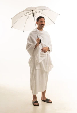 رجل سعودي بملابس الإحرام يحمل مظلة بيضاء
