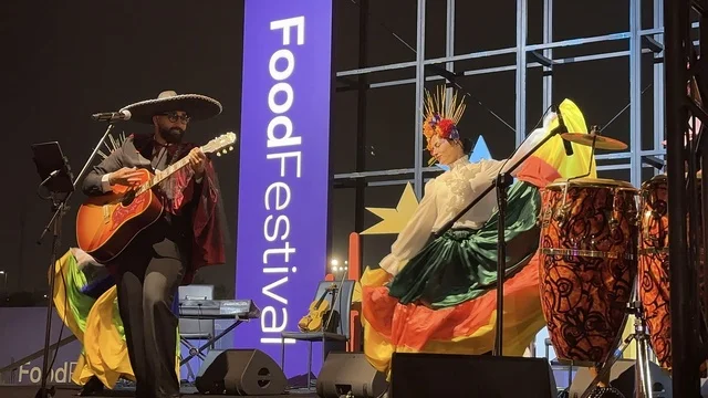 A musical performance with folkloric costumes and drumming at a food festival in the outdoor Ithra Gardens in Dhahran, Eastern Province, Saudi Arabia, on December 28, 2025. Family-friendly and entertaining atmosphere, a recreational and educational experience, international and local restaurants, enjoyable outdoor seating.
