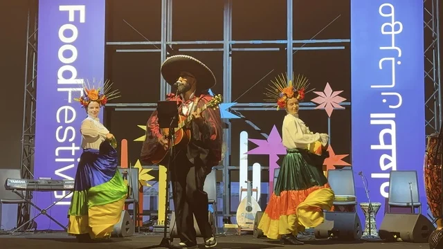 A musical performance and folkloric dance at a food festival in the outdoor Ithra Gardens in Dhahran, Eastern Province, Saudi Arabia, on December 28, 2025. Family-friendly and entertaining atmosphere, a recreational and educational experience, international and local restaurants, enjoyable outdoor seating.